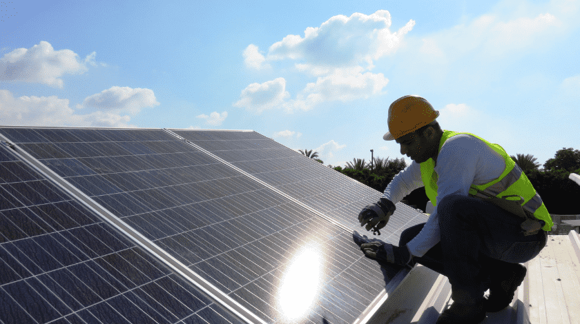 Solar panel technician installing solar panels on the roof of a house.